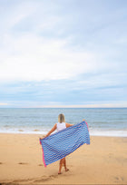 Person holding a blue and pink striped towel on a beach